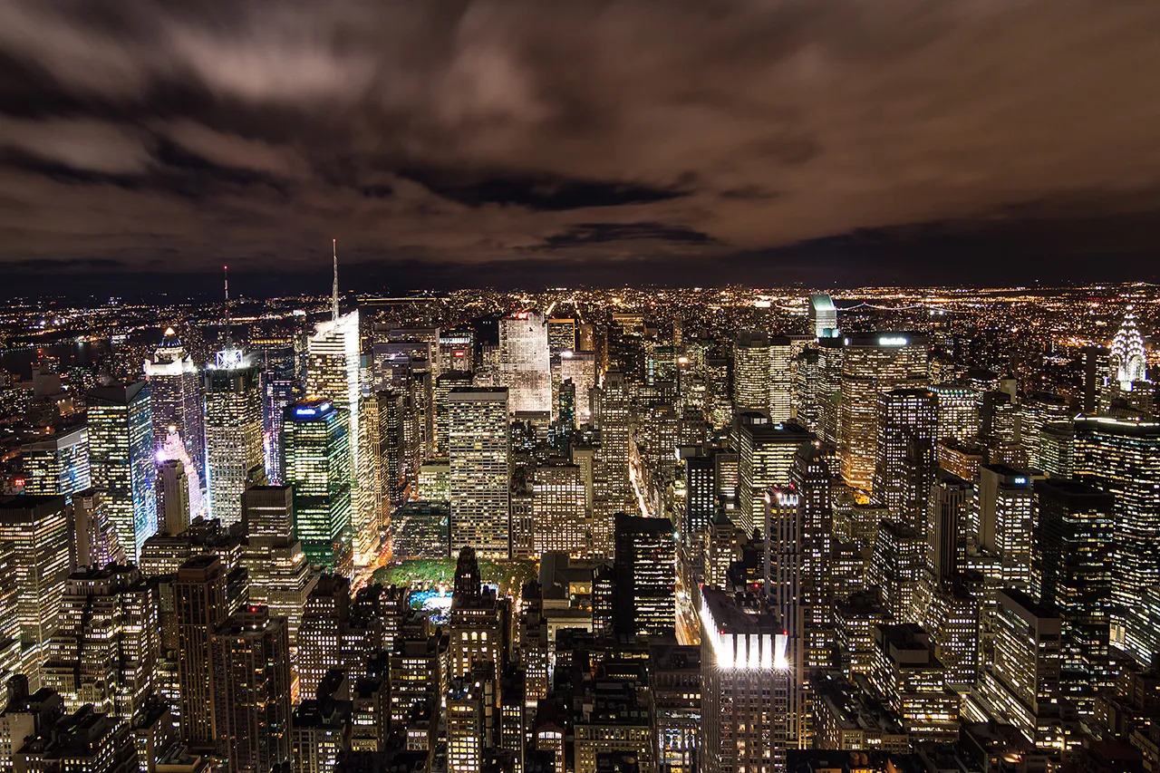 Noční pohled na zářící mrakodrapy Manhattanu v New Yorku z ptačí perspektivy.